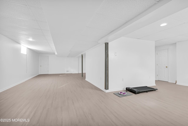 finished basement featuring a paneled ceiling, baseboards, and wood finished floors