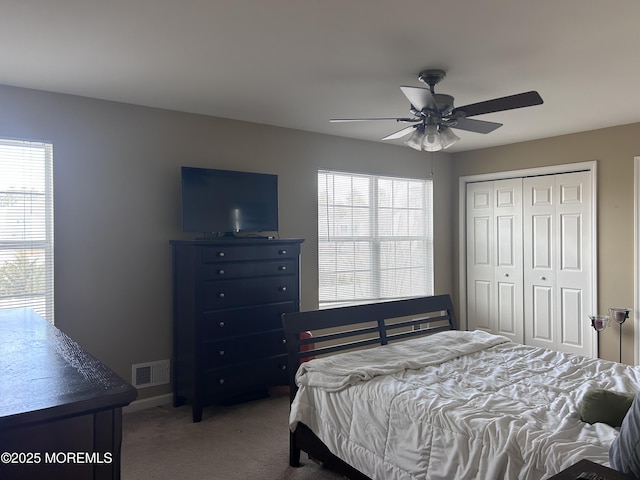 bedroom with a closet, multiple windows, visible vents, and carpet flooring