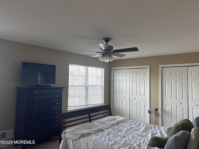 bedroom featuring multiple closets, visible vents, and a ceiling fan