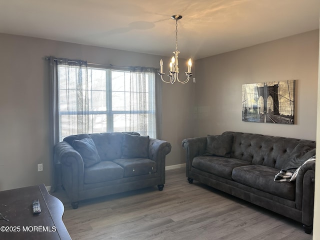 living area featuring baseboards, a chandelier, and wood finished floors