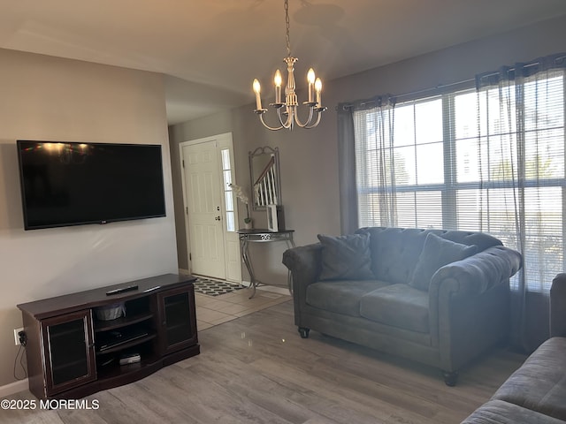 living room with baseboards, light wood finished floors, and an inviting chandelier