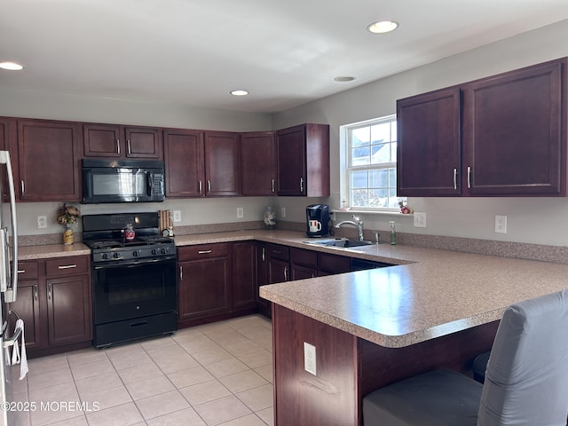 kitchen featuring a peninsula, a breakfast bar, a sink, light countertops, and black appliances