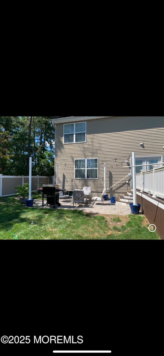 rear view of house featuring a yard, fence, and a patio