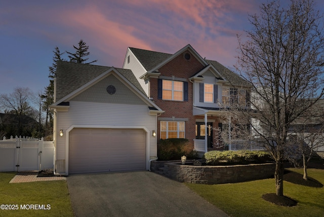 view of front facade featuring driveway, a gate, fence, a yard, and a garage