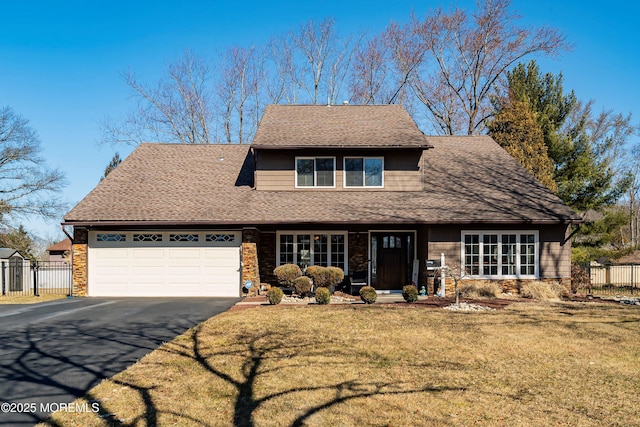 view of front of house featuring fence, driveway, roof with shingles, a front lawn, and a garage