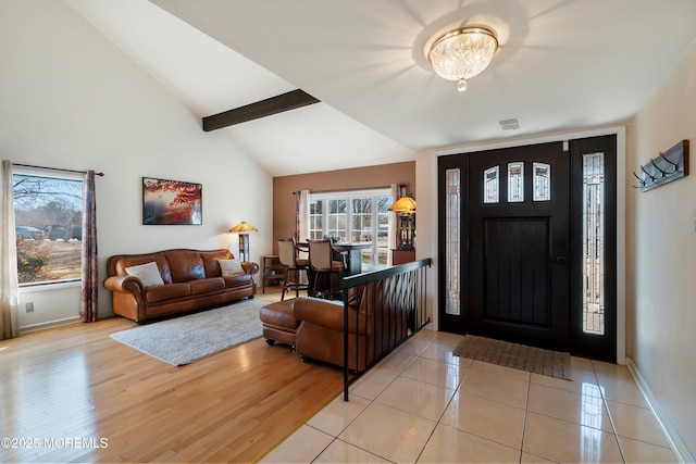 foyer with visible vents, baseboards, high vaulted ceiling, beam ceiling, and light wood-style floors