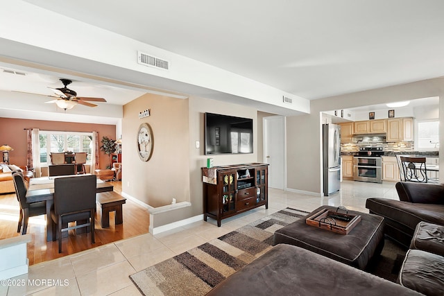 living area with light tile patterned floors, visible vents, and baseboards