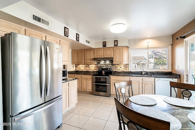 kitchen featuring visible vents, a sink, tasteful backsplash, appliances with stainless steel finishes, and light tile patterned flooring