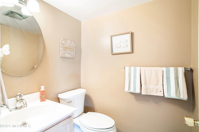 bathroom featuring visible vents, toilet, and vanity