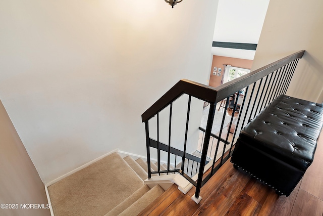 stairway featuring a high ceiling, wood finished floors, and baseboards