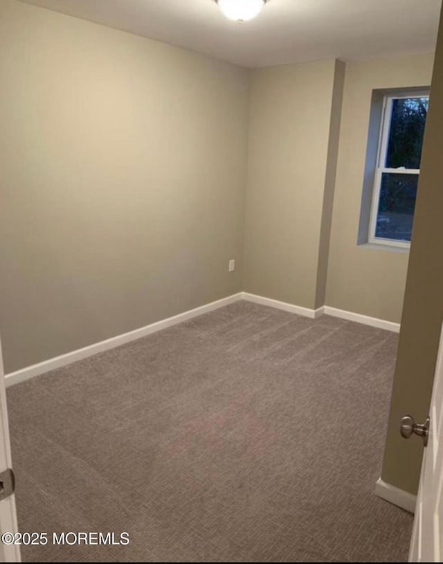 unfurnished room with dark colored carpet and baseboards