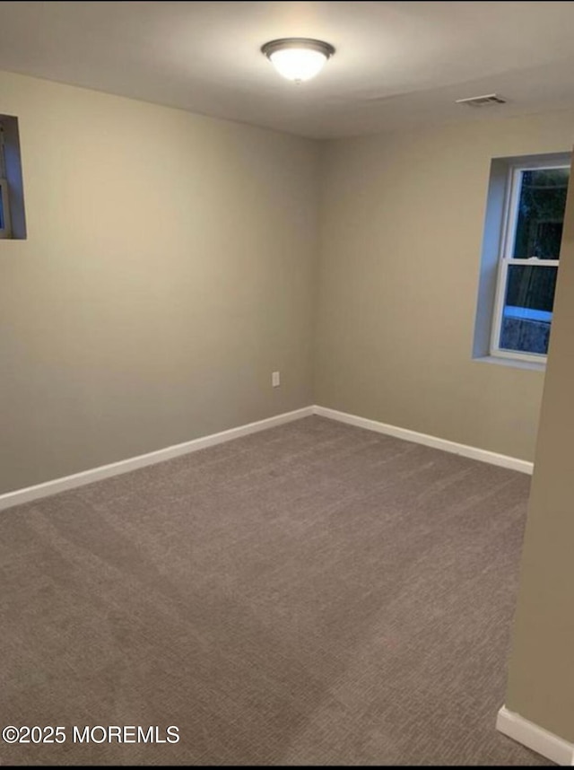 empty room with baseboards and dark carpet