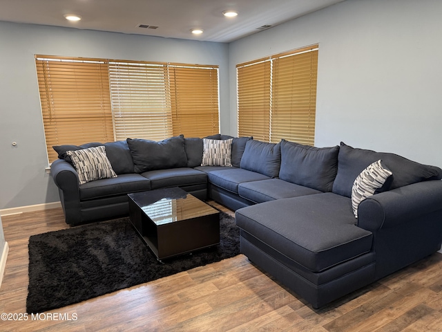 living room with visible vents, baseboards, wood finished floors, and recessed lighting