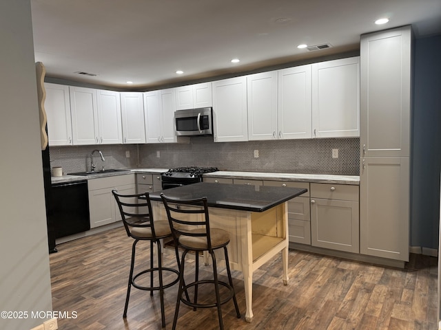 kitchen featuring appliances with stainless steel finishes, a breakfast bar, visible vents, and a sink