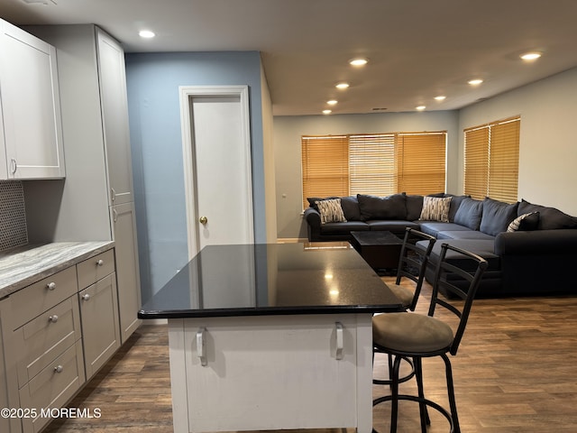 kitchen with a center island, dark wood-style flooring, recessed lighting, open floor plan, and a kitchen breakfast bar