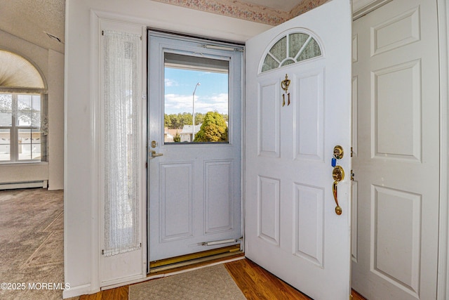 foyer entrance featuring a baseboard radiator and wood finished floors