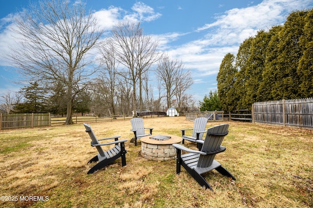 view of yard featuring a fire pit, a storage unit, an outbuilding, and a fenced backyard