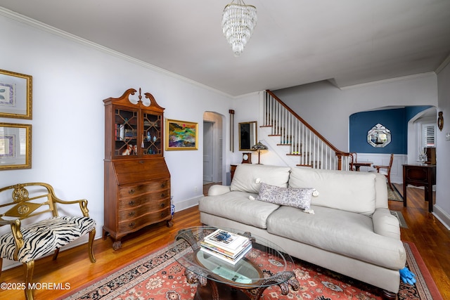living area with an inviting chandelier, crown molding, arched walkways, and wood finished floors