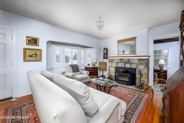 living area featuring a wood stove, crown molding, baseboards, and wood finished floors