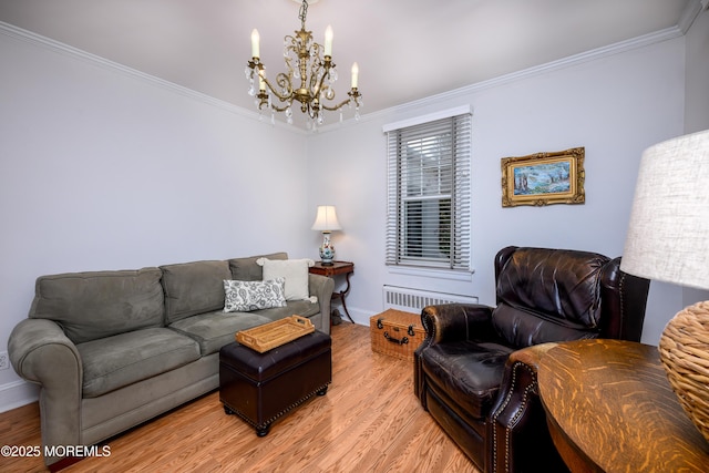 living area featuring radiator, a notable chandelier, crown molding, and light wood finished floors