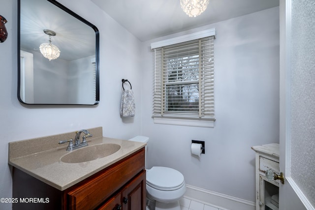half bath featuring a chandelier, baseboards, vanity, and toilet