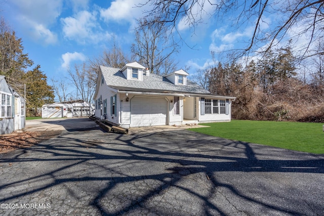 view of front of property with a shingled roof, a garage, driveway, and a front lawn