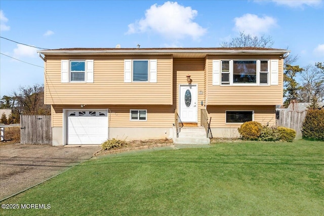 raised ranch with entry steps, fence, driveway, and a front lawn