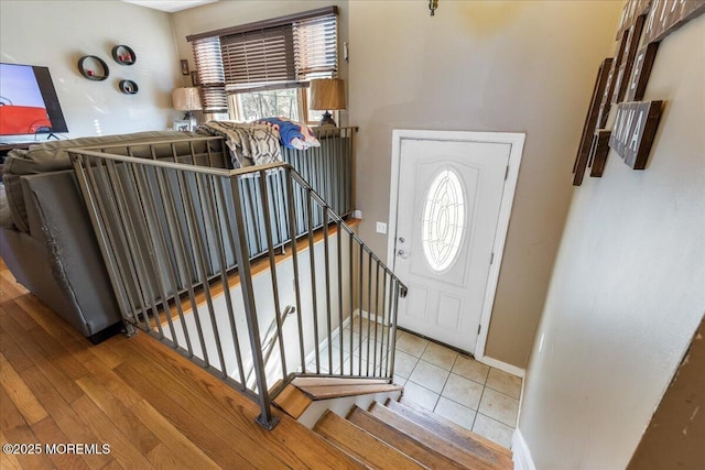 tiled foyer entrance with stairs and baseboards