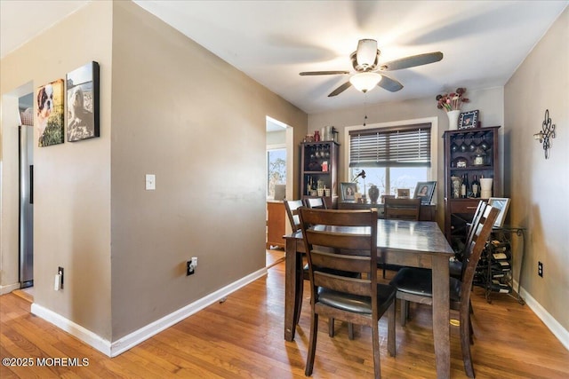 dining space featuring a ceiling fan, light wood-type flooring, and baseboards