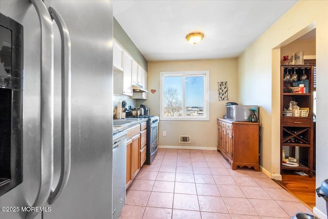 kitchen with light tile patterned floors, baseboards, visible vents, stainless steel appliances, and under cabinet range hood