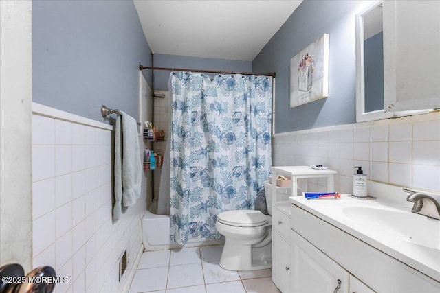 full bath with toilet, tile patterned flooring, shower / bath combo with shower curtain, vanity, and tile walls