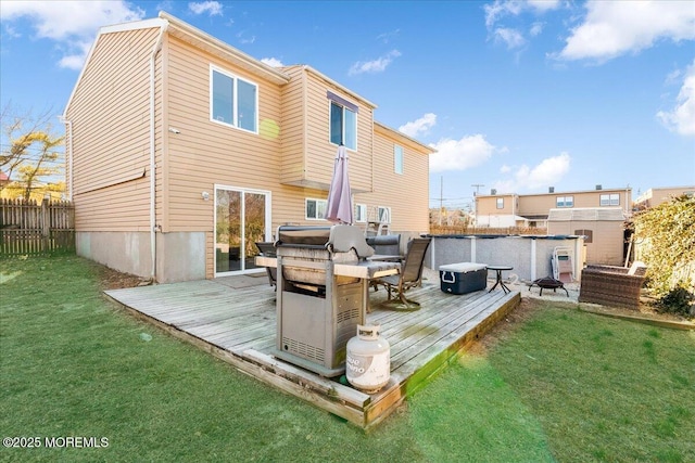 back of property featuring fence, a deck, and a lawn