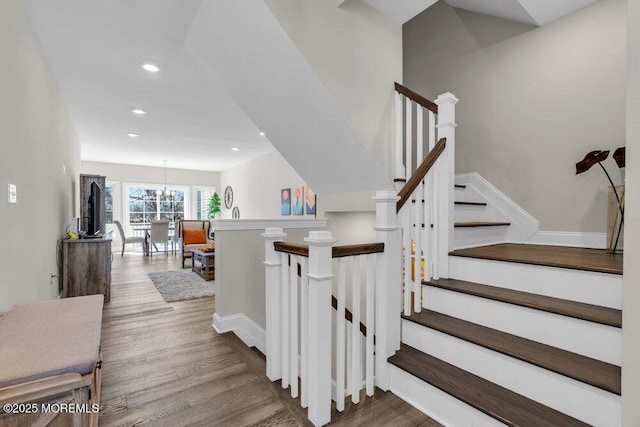 stairway with recessed lighting, a notable chandelier, baseboards, and wood finished floors