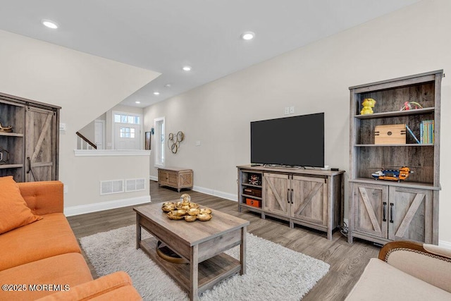 living room with recessed lighting, visible vents, baseboards, and wood finished floors