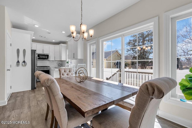 dining space featuring an inviting chandelier, light wood-style flooring, baseboards, and recessed lighting