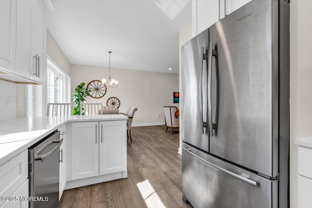 kitchen featuring backsplash, white cabinetry, stainless steel appliances, and wood finished floors