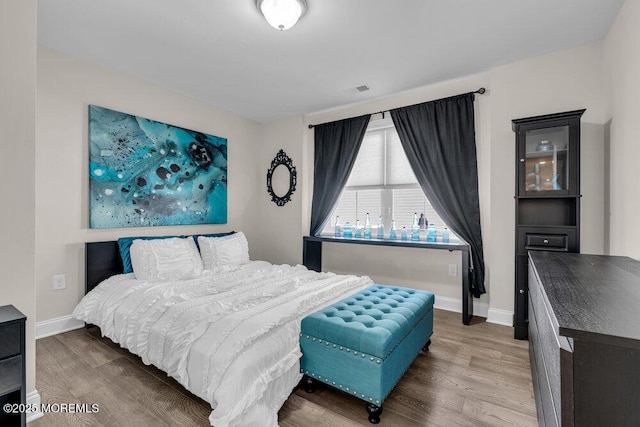 bedroom with visible vents, baseboards, and wood finished floors