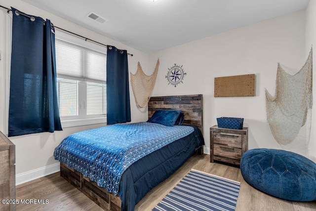 bedroom featuring wood finished floors, visible vents, and baseboards