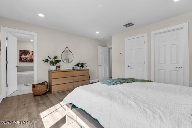 bedroom with ensuite bath, wood finished floors, visible vents, and recessed lighting