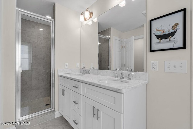 bathroom with double vanity, a shower stall, and a sink