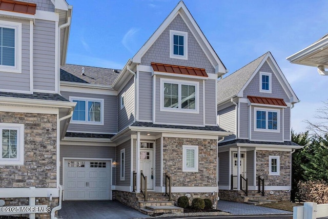 view of front of home featuring a garage, stone siding, a shingled roof, and driveway