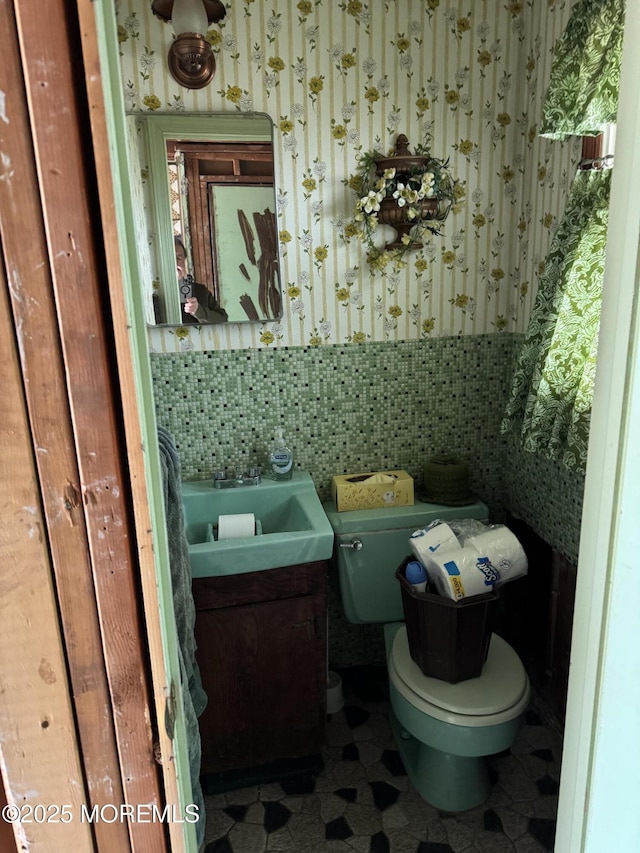 bathroom featuring toilet, wallpapered walls, tasteful backsplash, and vanity