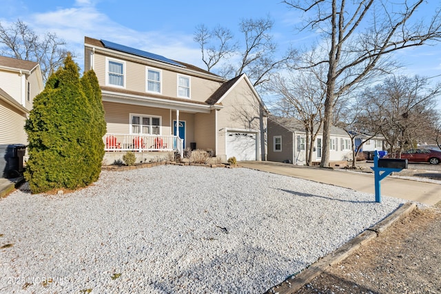 traditional home featuring a garage, covered porch, driveway, and roof mounted solar panels