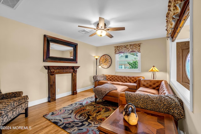 living area featuring a ceiling fan, visible vents, baseboards, and wood finished floors