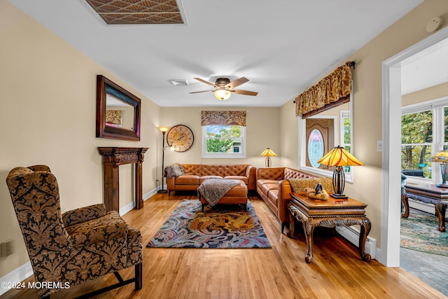 living room featuring a baseboard radiator, a wealth of natural light, visible vents, and wood finished floors