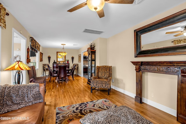 living room featuring baseboards, wood finished floors, visible vents, and a ceiling fan