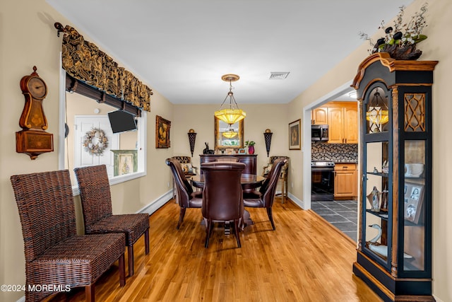 dining space with light wood-style flooring, baseboard heating, visible vents, and baseboards