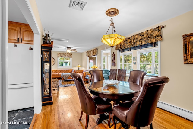 dining area with light wood-type flooring, a baseboard radiator, and visible vents