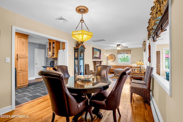 dining room featuring a baseboard heating unit, visible vents, dark wood finished floors, and baseboards