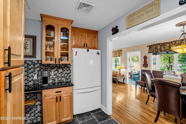 kitchen featuring dark countertops, visible vents, backsplash, glass insert cabinets, and freestanding refrigerator